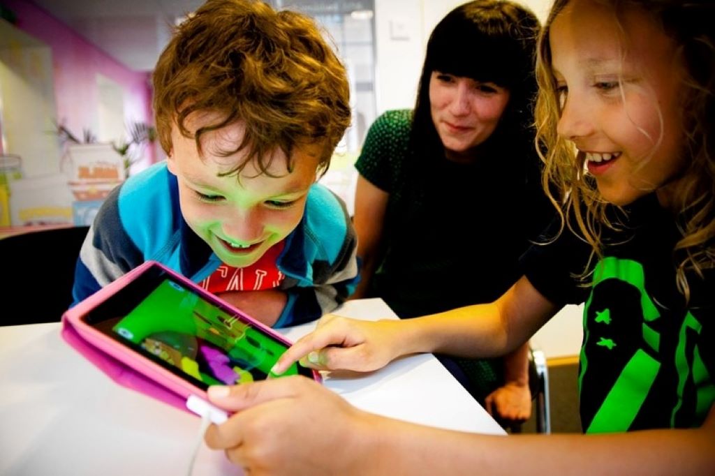 Children playing Toca Boca game on tablet with multiple unlocked characters visible on screen