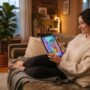 Adult relaxing on a living room couch playing a puzzle game on a tablet.