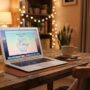 A cozy desk setup with a laptop displaying a relaxing online game next to tea.