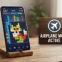 Hand holding smartphone playing colorful match 3 puzzle game in airplane mode.