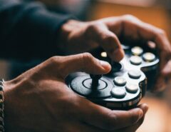 Male gamer executing fast button inputs on a glowing fight stick.