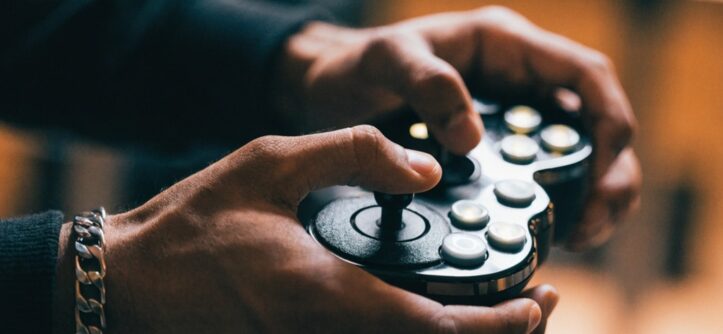 Male gamer executing fast button inputs on a glowing fight stick.