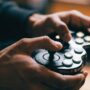 Male gamer executing fast button inputs on a glowing fight stick.