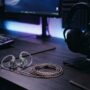 In-ear monitors placed next to an over-ear headset on a gaming desk.